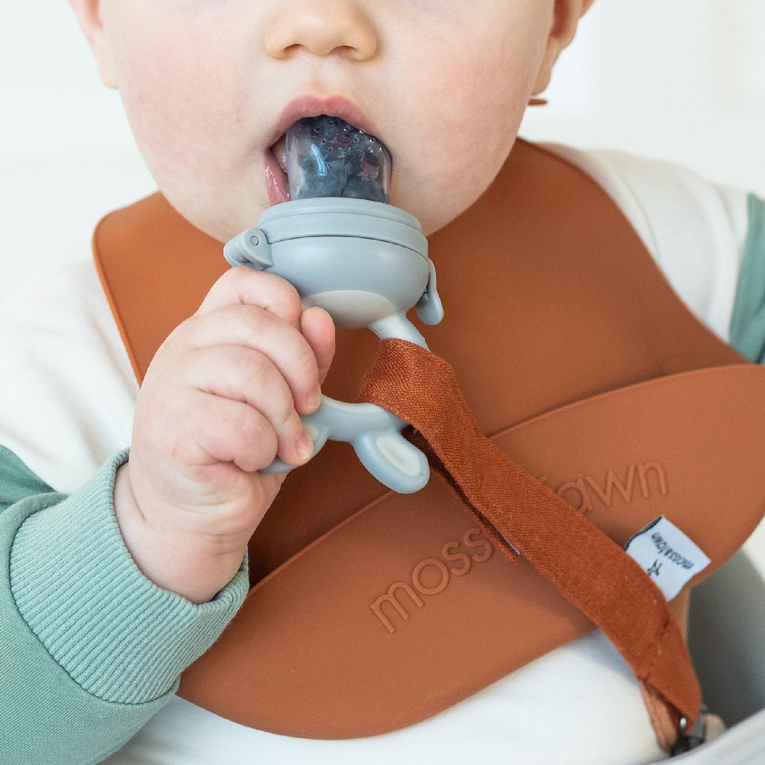 Baby showing signs of teething at 2 months using fruit-filled feeder