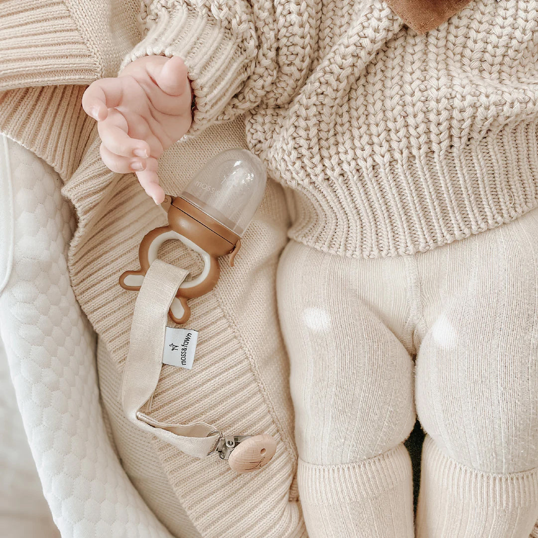 a photo of a forage feeder and a baby in an adorable sweater