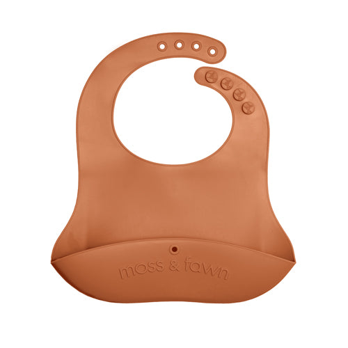 A brown silicone bib with adjustable neck straps and a brand logo 'moss & Fawn' printed on the bottom.